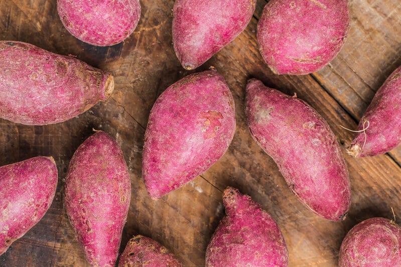 batata doces rosadas sobre uma mesa de tábuas